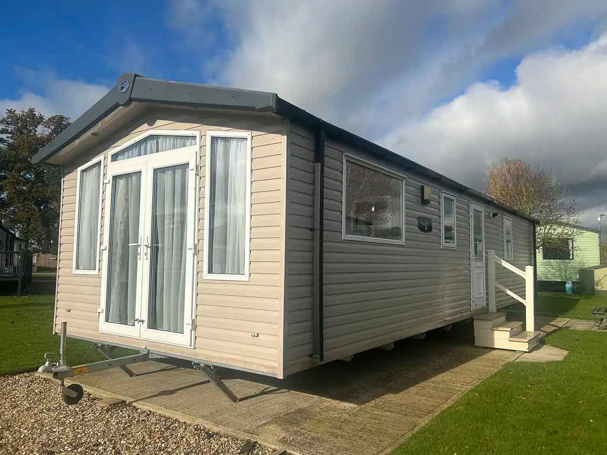 Swift Biarritz Holiday Home Exterior Swift Biarritz static caravan with modern white cladding and large front windows in a holiday park